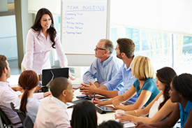 Businesswoman addressing meeting around boardroom table