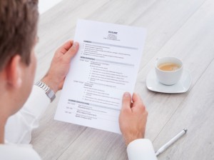 Businessman Reading Resume With Tea Cup On Desk